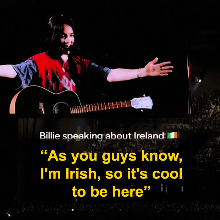 Billie Eilish performing on stage with a guitar, speaking during her Ireland show amid racism controversy. Billie Eilish performing on stage with a guitar, speaking during her Ireland show amid racism controversy.