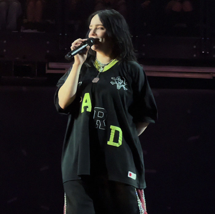 Billie Eilish performing on stage at a concert, holding a microphone during her Ireland show controversy. Billie Eilish performing on stage at a concert, holding a microphone during her Ireland show controversy.