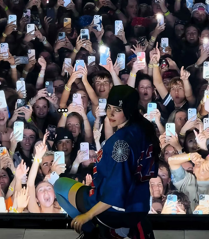 Billie Eilish performing on stage with fans holding up phones during concert amid controversy over comment in Ireland. Billie Eilish performing on stage with fans holding up phones during concert amid controversy over comment in Ireland.