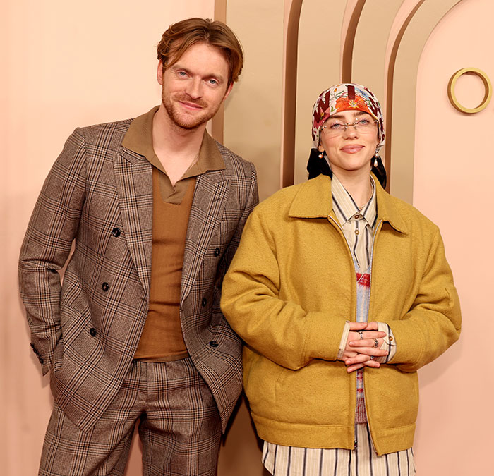 Billie Eilish at an event with a male companion, both dressed stylishly, amid media coverage on her Ireland show controversy. Billie Eilish at an event with a male companion, both dressed stylishly, amid media coverage on her Ireland show controversy.