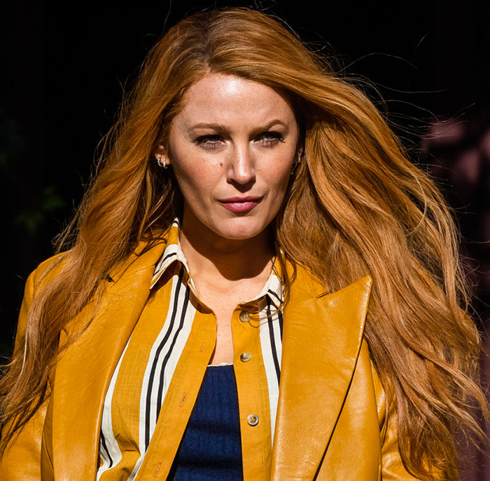 Blake Lively wearing a mustard yellow jacket walking outdoors with hair flowing, capturing a confident court reality check moment Blake Lively wearing a mustard yellow jacket walking outdoors with hair flowing, capturing a confident court reality check moment
