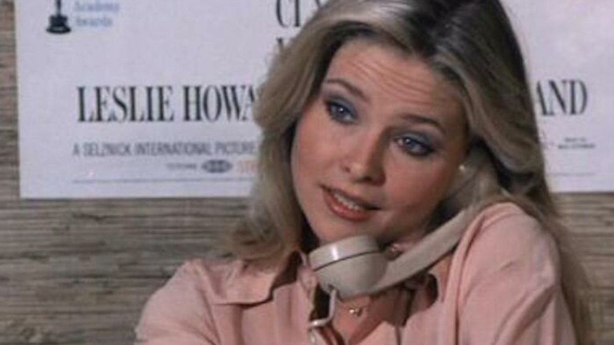 Bond Girl talking on a telephone in a vintage scene from a film with Timothy Dalton, showcasing classic 1980s style.