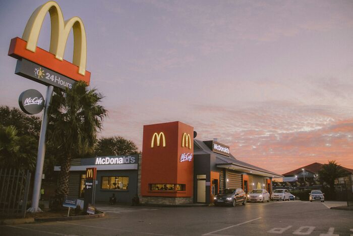 McDonald's employees outside a restaurant during sunset sharing bizarre experiences from their work shifts.