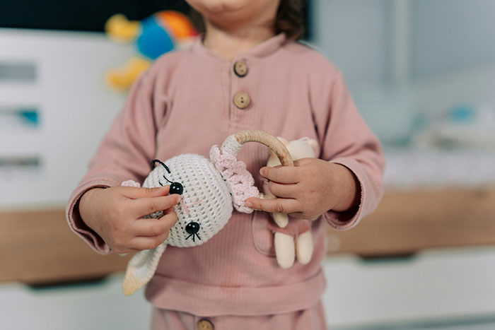 Young child holding a handmade toy in a cozy room, highlighting the theme of a man canceling plans to avoid watching his daughter. Young child holding a handmade toy in a cozy room, highlighting the theme of a man canceling plans to avoid watching his daughter.