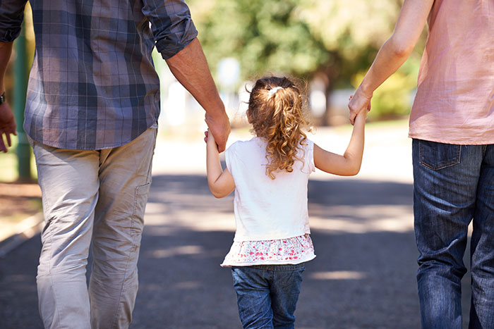 Man holding daughter's hand walking outdoors with woman, highlighting cycle trip choice over watching daughter scenario. Man holding daughter's hand walking outdoors with woman, highlighting cycle trip choice over watching daughter scenario.
