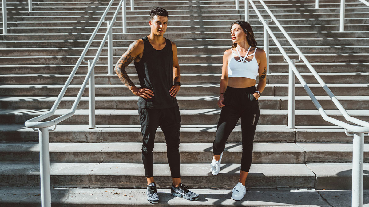 Two fit young adults in workout clothes standing on concrete stairs symbolizing weight loss before wedding conflict.
