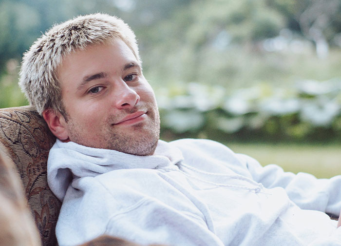 Young man in a white hoodie relaxing outdoors, representing men getting brutally honest about topics they never share with women.