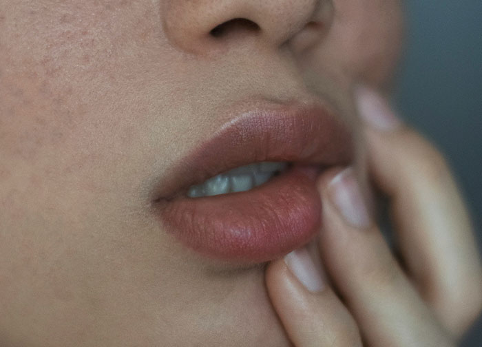 Close-up of a person’s lips and fingers, highlighting raw emotion and honesty in personal expression.