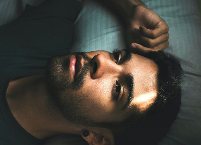 A man lying down with a thoughtful expression, illustrating men being brutally honest about what they never tell women.