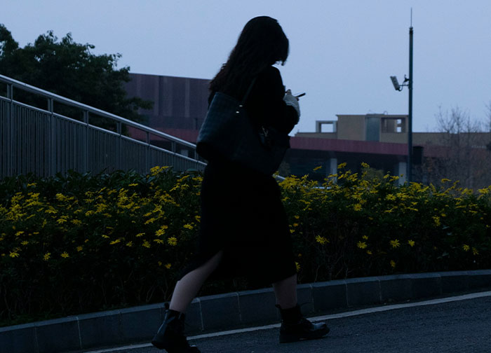 Silhouetted woman walking alone near yellow flowers at dusk, capturing the theme of men brutally honest and sharing feelings.