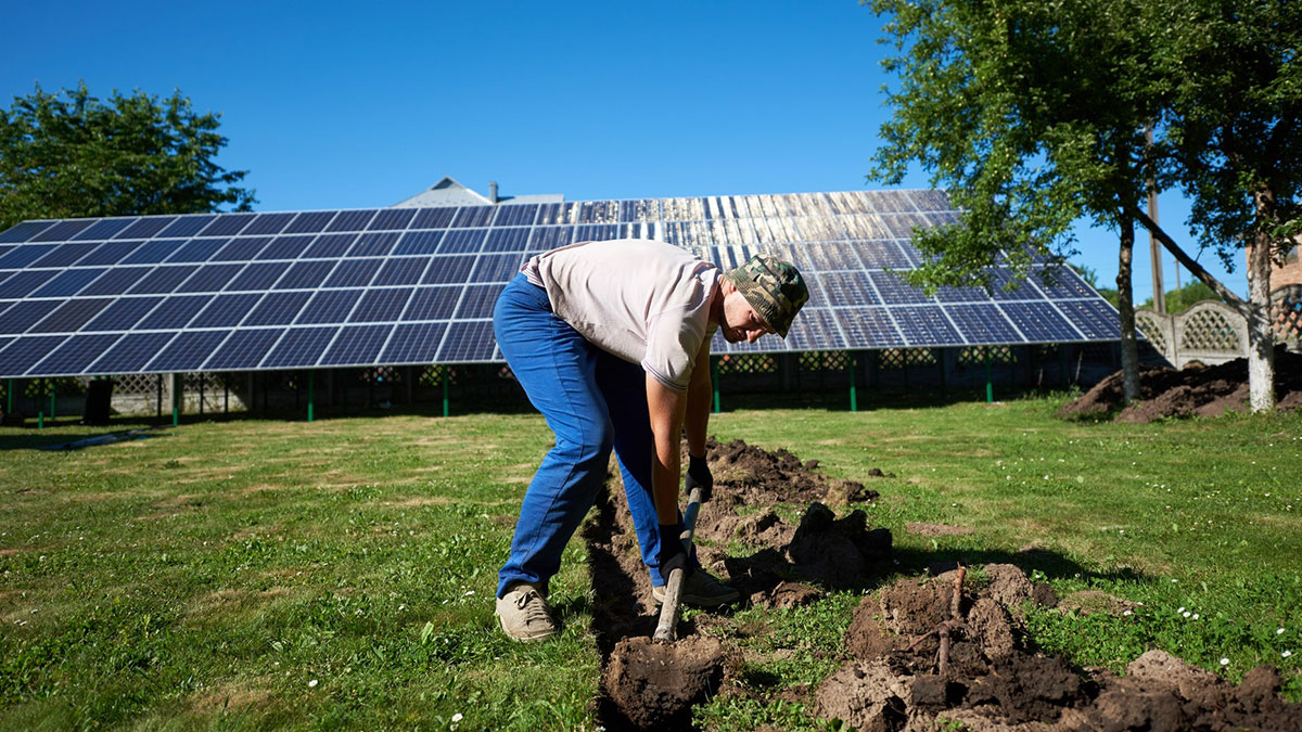 Worker digging near solar panels at a construction site where a 5000-year-old fortress was uncovered during excavation.