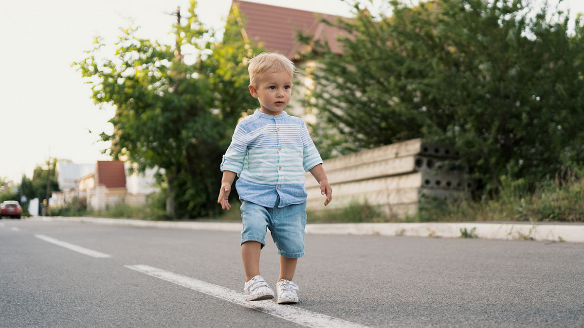 Toddler walking alone on a suburban street, highlighting concern that led neighbor to call cops on 2YO wandering alone.