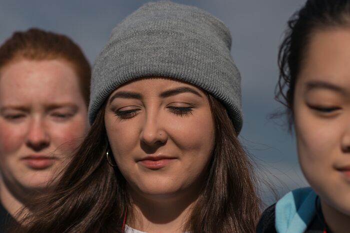 Three young women with eyes closed outdoors, illustrating bizarre beliefs people still fall for despite myth busted by science.