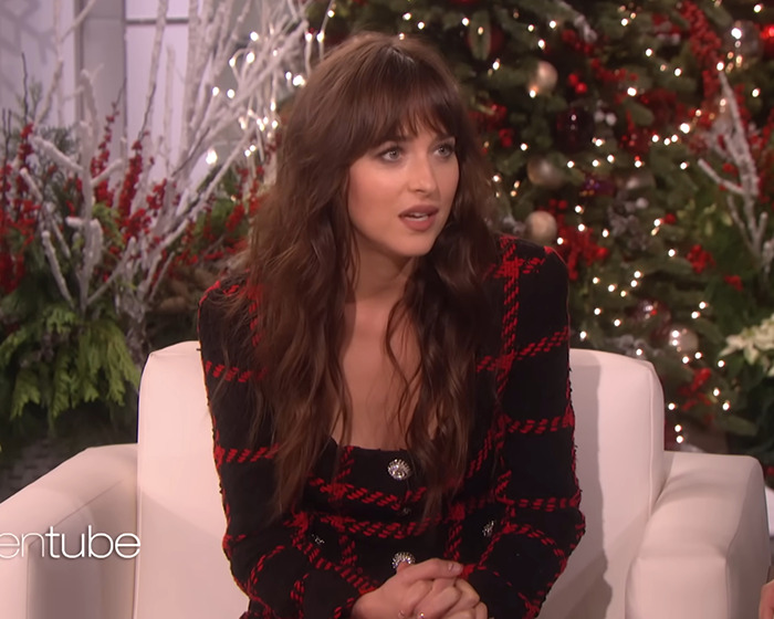 Woman in black and red checkered outfit sitting on white chair with festive Christmas tree in the background discussing Céline Dion fans and Ellen interview. Woman in black and red checkered outfit sitting on white chair with festive Christmas tree in the background discussing Céline Dion fans and Ellen interview.
