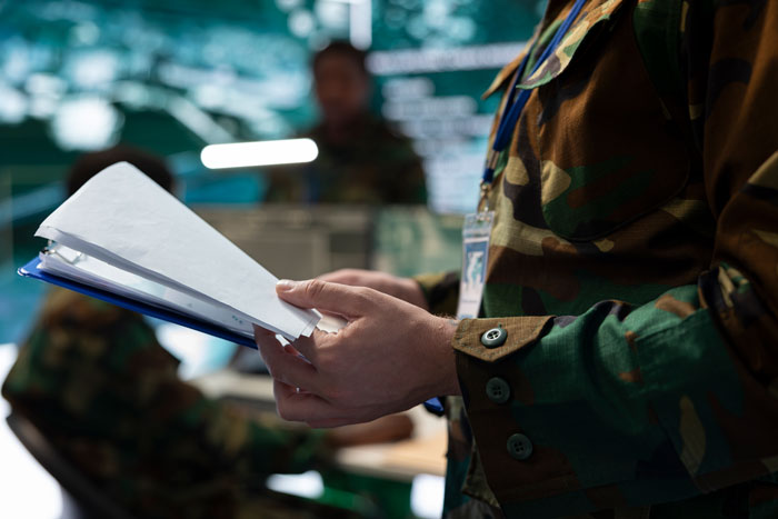 Soldier reviewing report on missing equipment, tracking loss for months, confronting his boss in a military setting. Soldier reviewing report on missing equipment, tracking loss for months, confronting his boss in a military setting.