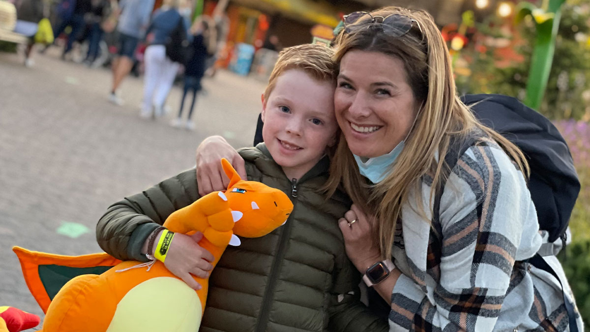 Mom claps back at exu2019s family with screenshots, smiling and hugging child holding an orange plush toy outdoors.