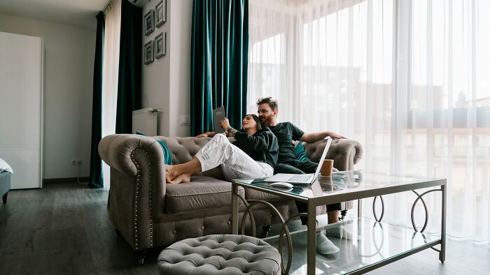 Couple relaxing on sofa in living room, highlighting refusal to be go-to nanny on friends’ couples trip. Couple relaxing on sofa in living room, highlighting refusal to be go-to nanny on friends’ couples trip.