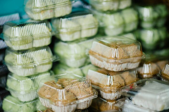 Plastic containers filled with packaged food stacked together highlighting the global food waste crisis issue.