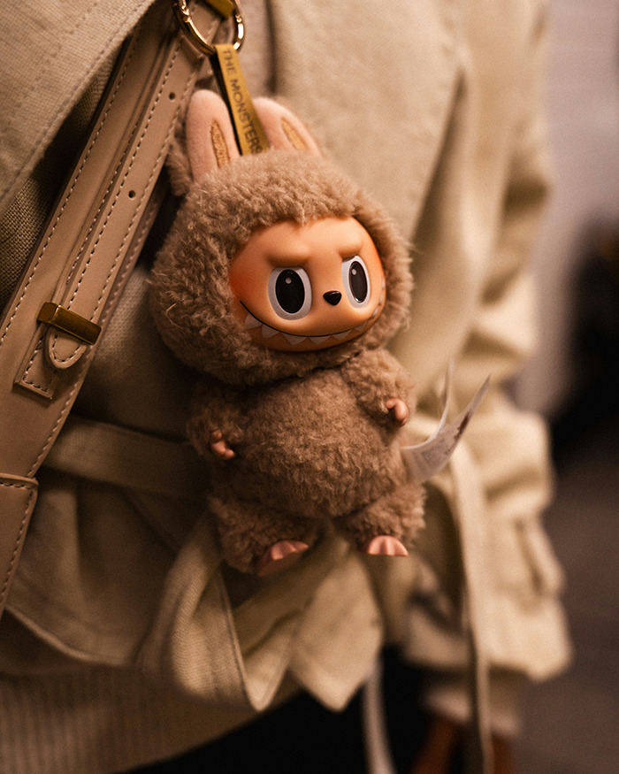 Labubu keychain with a dark conspiracy theme hanging from a beige bag, highlighting city bans and related concerns. Labubu keychain with a dark conspiracy theme hanging from a beige bag, highlighting city bans and related concerns.