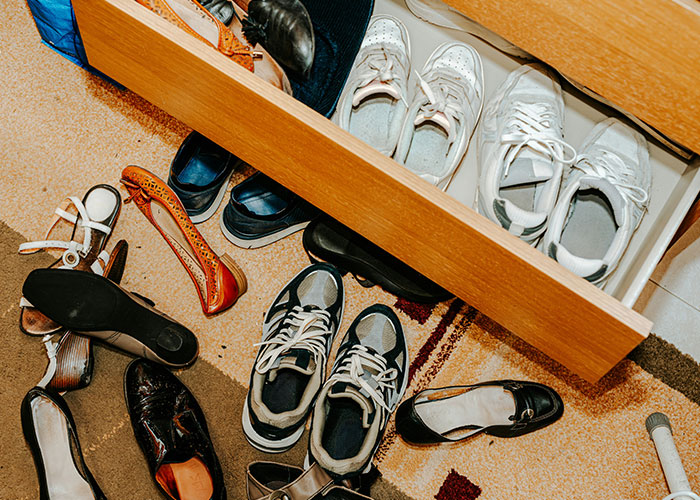 Messy college students' shoes scattered on the floor and inside a drawer, illustrating roommates finally picking up after themselves. Messy college students' shoes scattered on the floor and inside a drawer, illustrating roommates finally picking up after themselves.