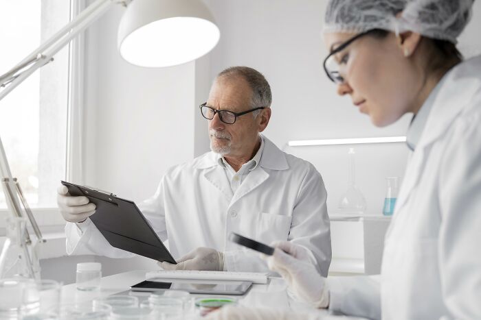 Two scientists in lab coats and glasses examining data while researching bodies donated for science use.