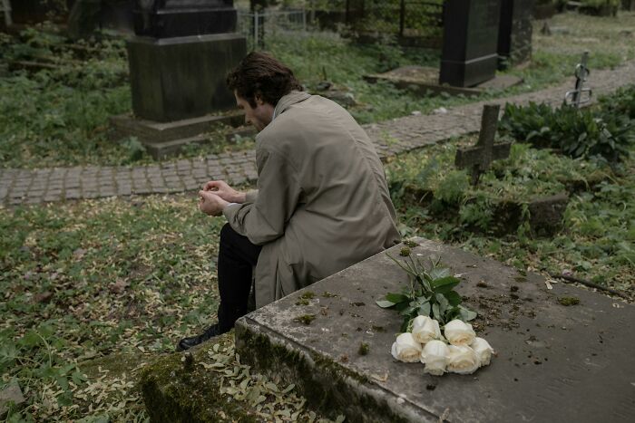 Man sitting alone in a graveyard, appearing distressed and contemplative, symbolizing mental struggle and despair.