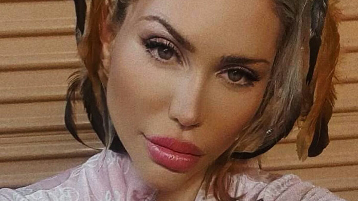 Reality star with braided hair posing in front of a wooden wall, linked to m****r investigation keywords.