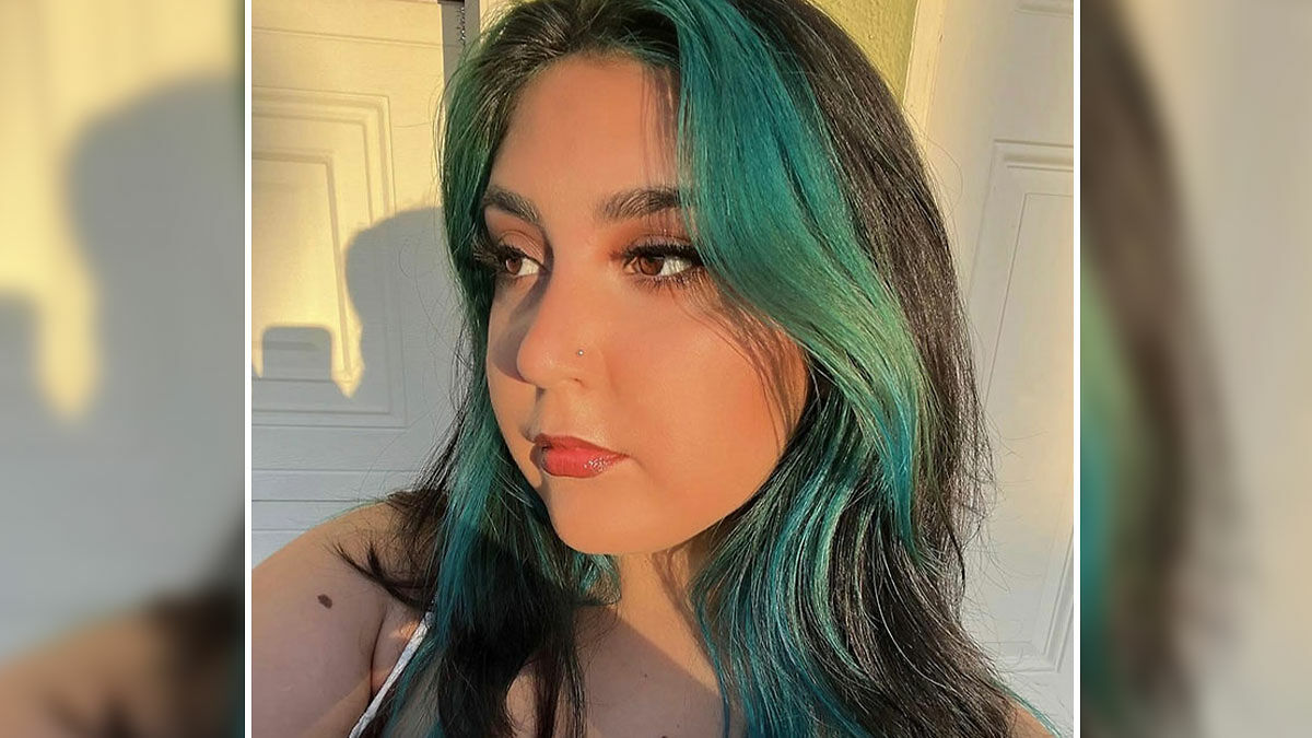 Young woman with teal and black hair looking sideways in natural light, related to 7-Eleven worker passing news.