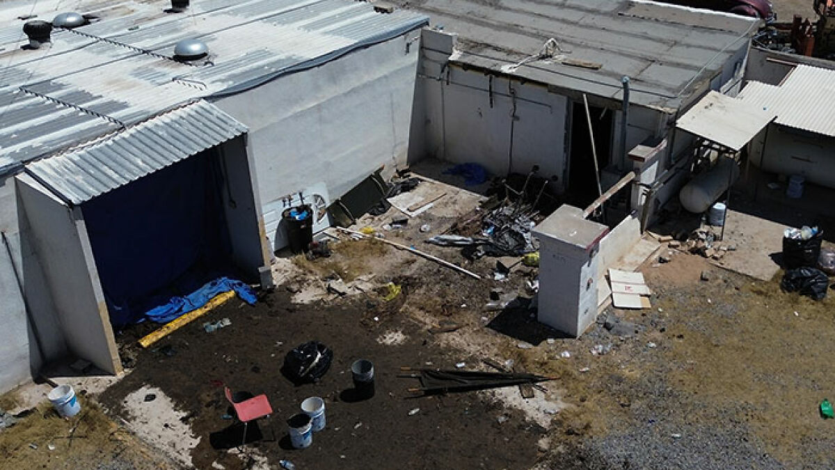 Abandoned building exterior with scattered debris and open doors linked to cops discovering nearly 400 human bodies.