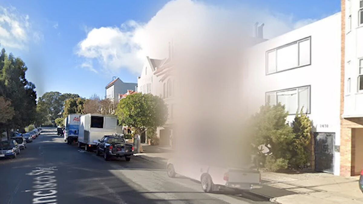 Residential street with several parked vehicles and one house intentionally blurred on Google Maps for privacy reasons.