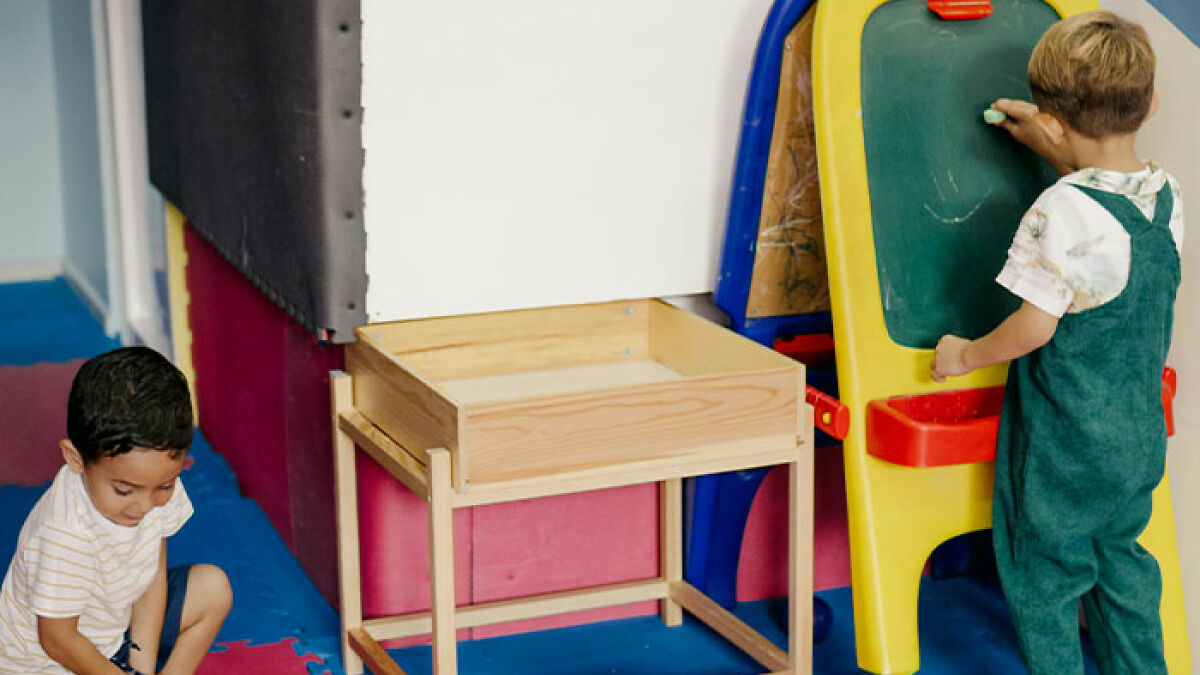 Two young children playing and drawing inside a classroom, related to child behavior and parenting topics.