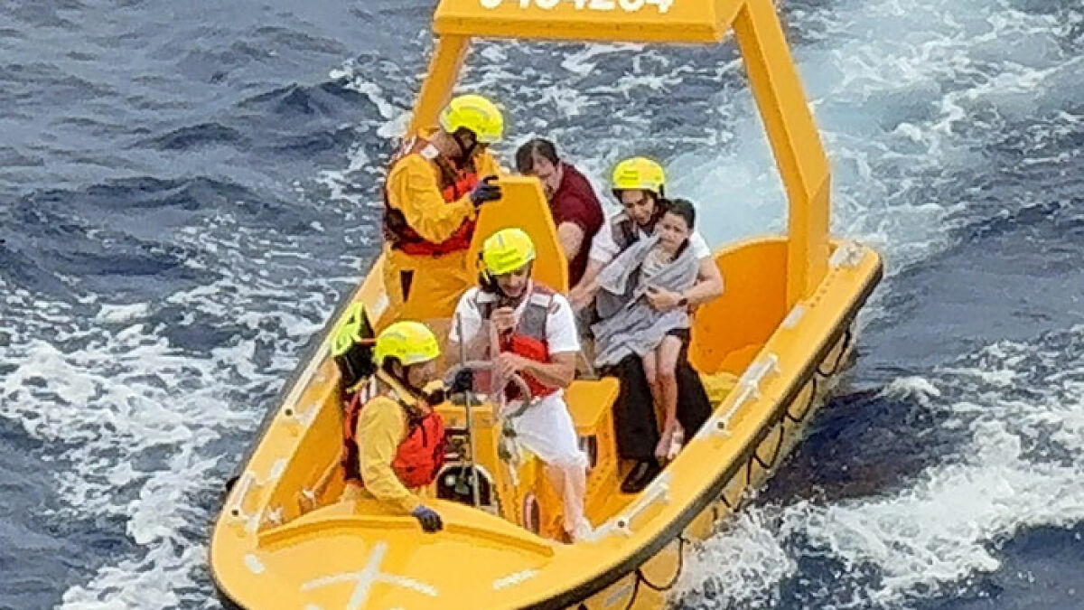 Rescue team in yellow gear aboard a boat on rough sea waters saving a child after falling off a cruise ship.