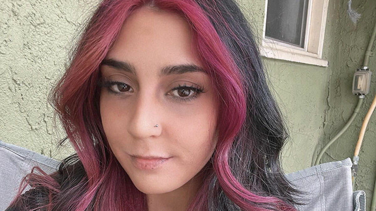 Young woman with pink and black hair sitting outdoors, related to police update on 7-Eleven employee passing away