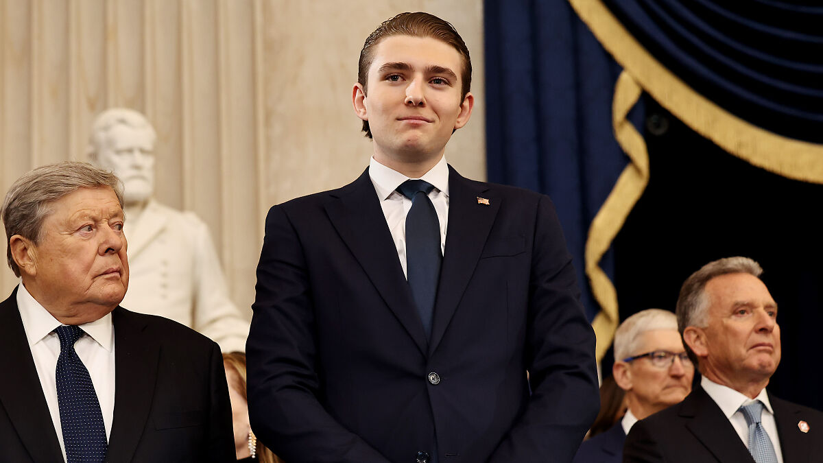 Barron Trump in a dark suit at a formal event, highlighting his luxury-filled childhood in the public spotlight.