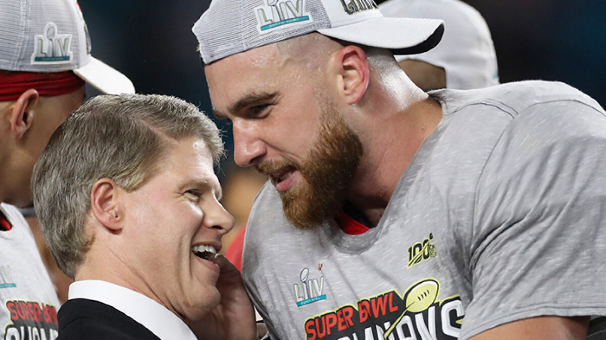 Man in suit and football player in gray Super Bowl LIV shirt and cap sharing a moment after a game in Texas floods tragedy news.