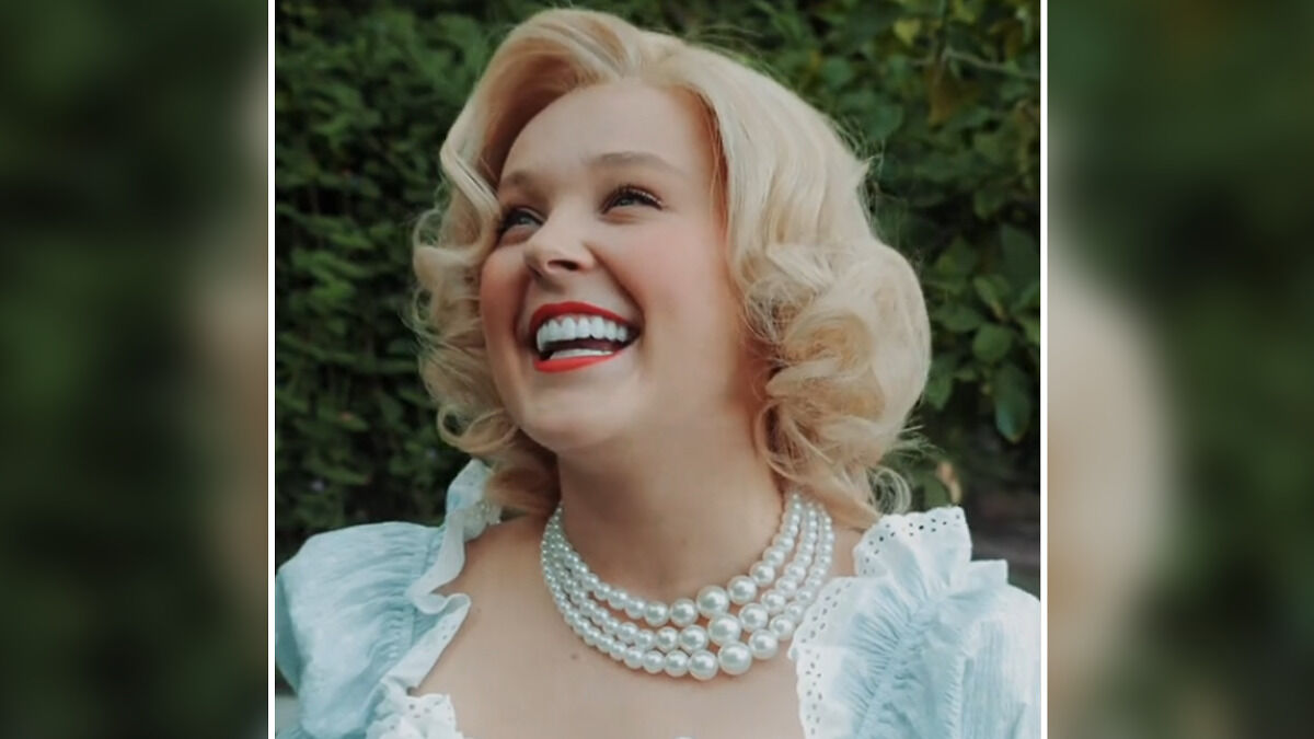 Blonde woman with vintage curls and pearl necklace smiling outdoors, related to JoJo Siwa straight pop transformation.