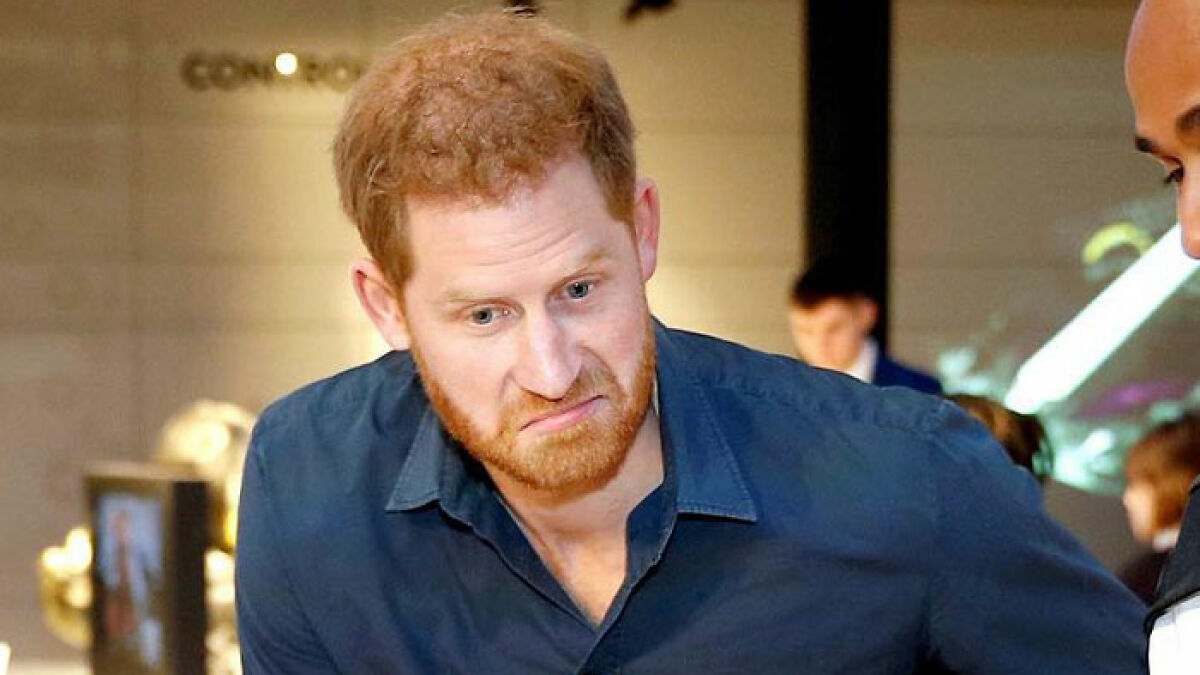 Prince Harry looking serious in a casual blue shirt, highlighting royal family tensions during Windsor Castle event.