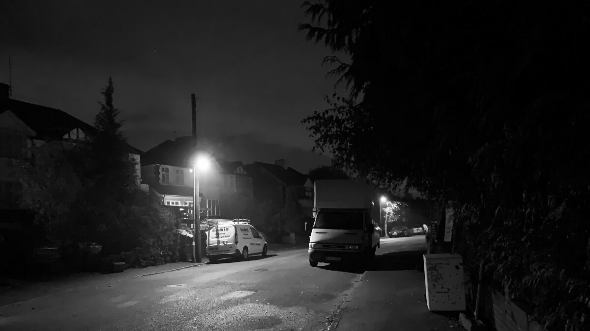 Dark quiet suburban street at night with parked vehicles, resembling a scene from a horror movie but actually peaceful.
