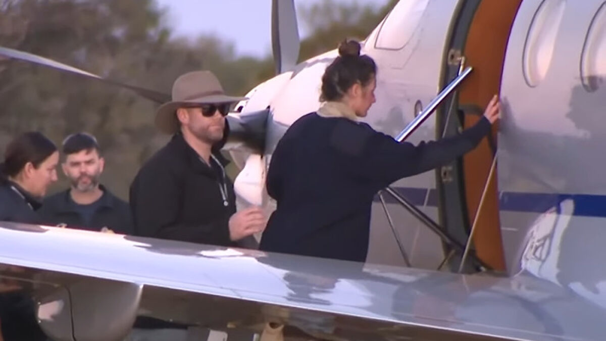 Backpacker found after 12 days in Australian outback boards plane with rescuers nearby during sunset.