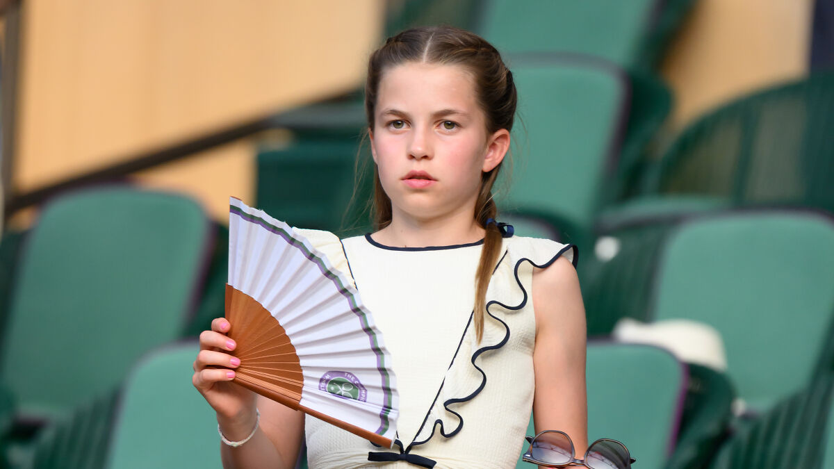 Princess Charlotte at Wimbledon final showing her colorful nail polish while holding a fan in the stands.