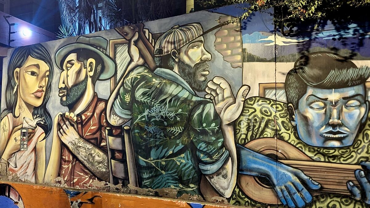 Colorful Barranco murals depicting people playing guitar and interacting, vibrant street art scene at night.