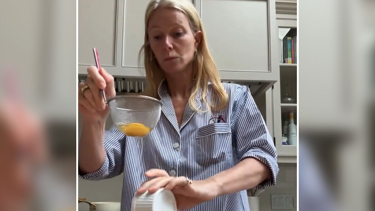 Gwyneth Paltrow in kitchen, handling cooking ingredients with focused expression, showing unusual trash-handling skills.
