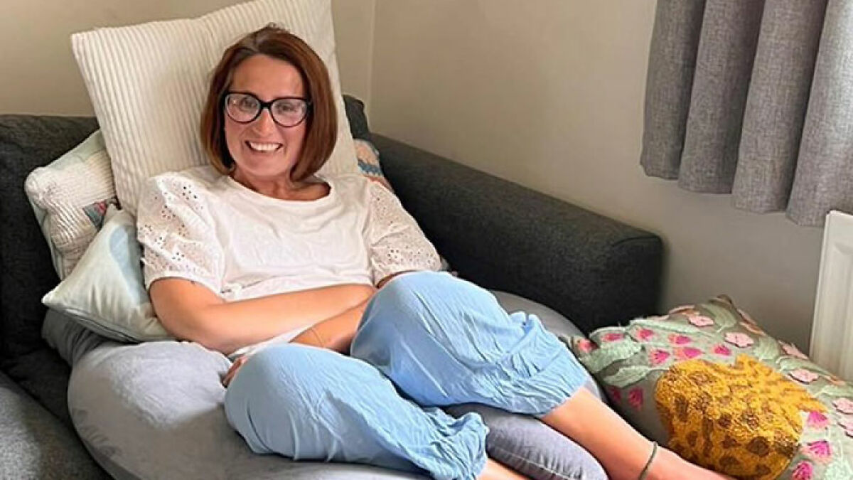 Woman with glasses relaxing on a couch among pillows, related to mom ends life by starving to protect kids story.