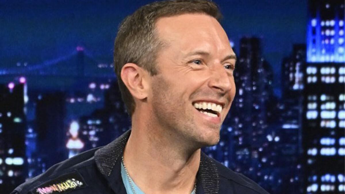 Chris Martin smiling during an interview, discussing the viral cheating scandal at the Coldplay concert.