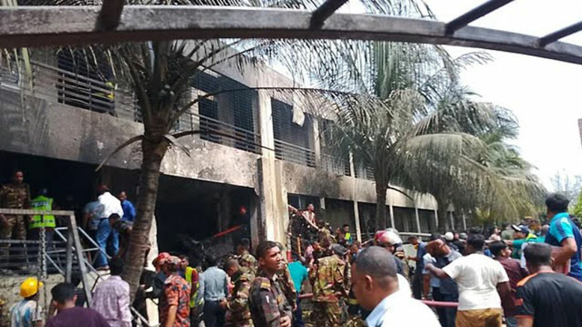 Fighter jet crashes into school building during class, emergency responders and crowd gather at the damaged site amid destruction.
