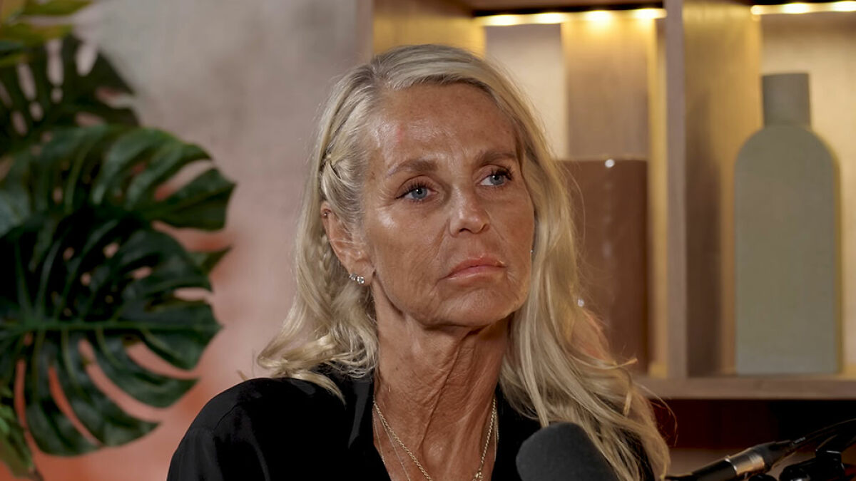 Ulrika Jonsson with over-tanned face, wearing black top, speaking in an emotional post shutting down trolls indoors.