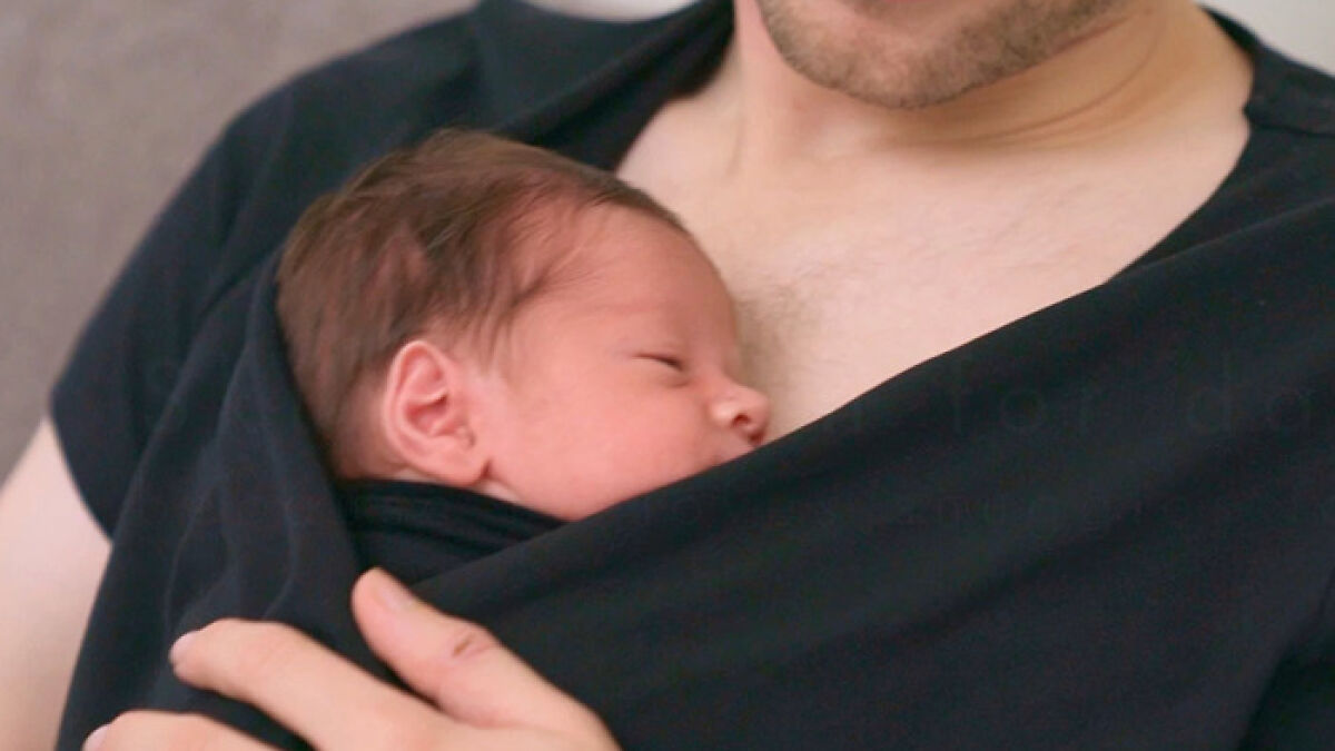 Newborn baby girl resting on fatheru2019s chest during close skin-to-skin contact in a gentle embrace.