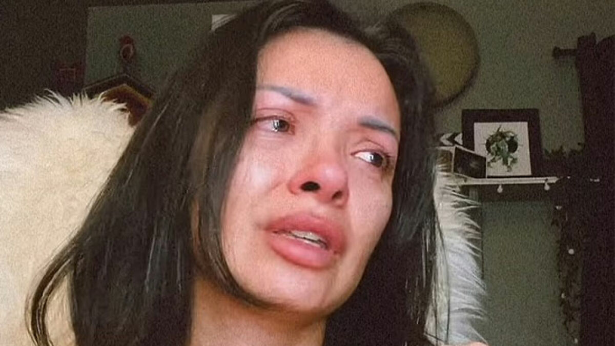 Woman with dark hair crying, claiming her $6,640 nose job damaged her face and caused emotional distress.