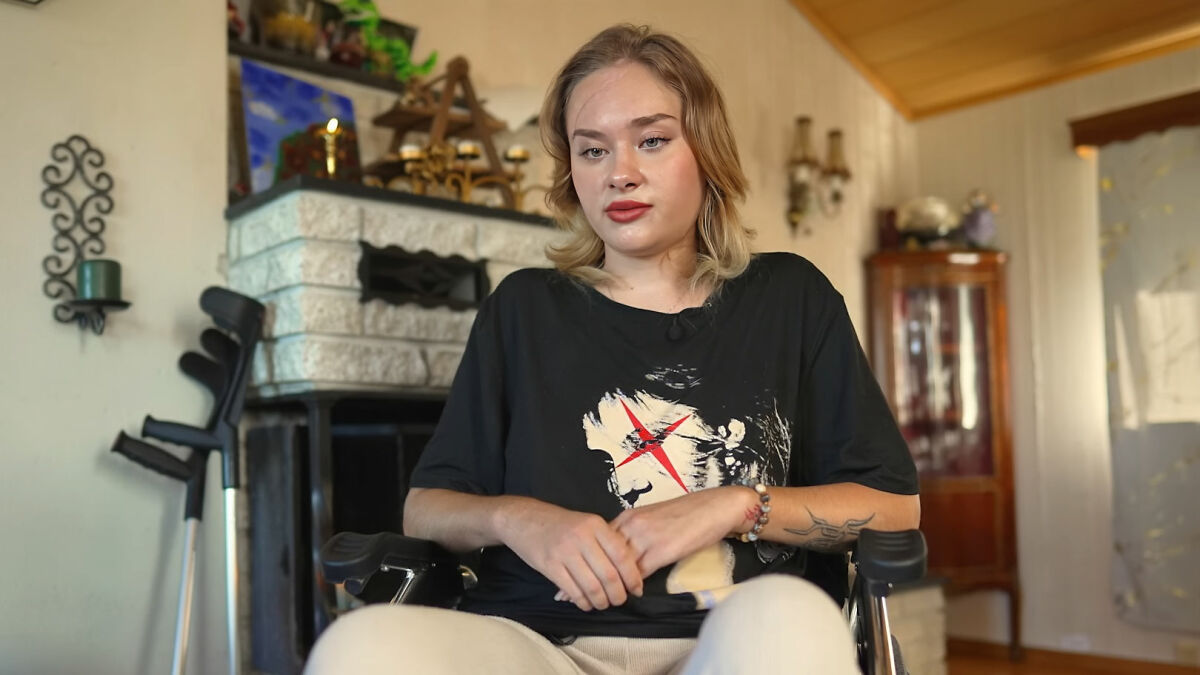 Young woman with crutches in the background, sitting indoors, discussing being scalped before rich kids dumped her roadside in Dubai.