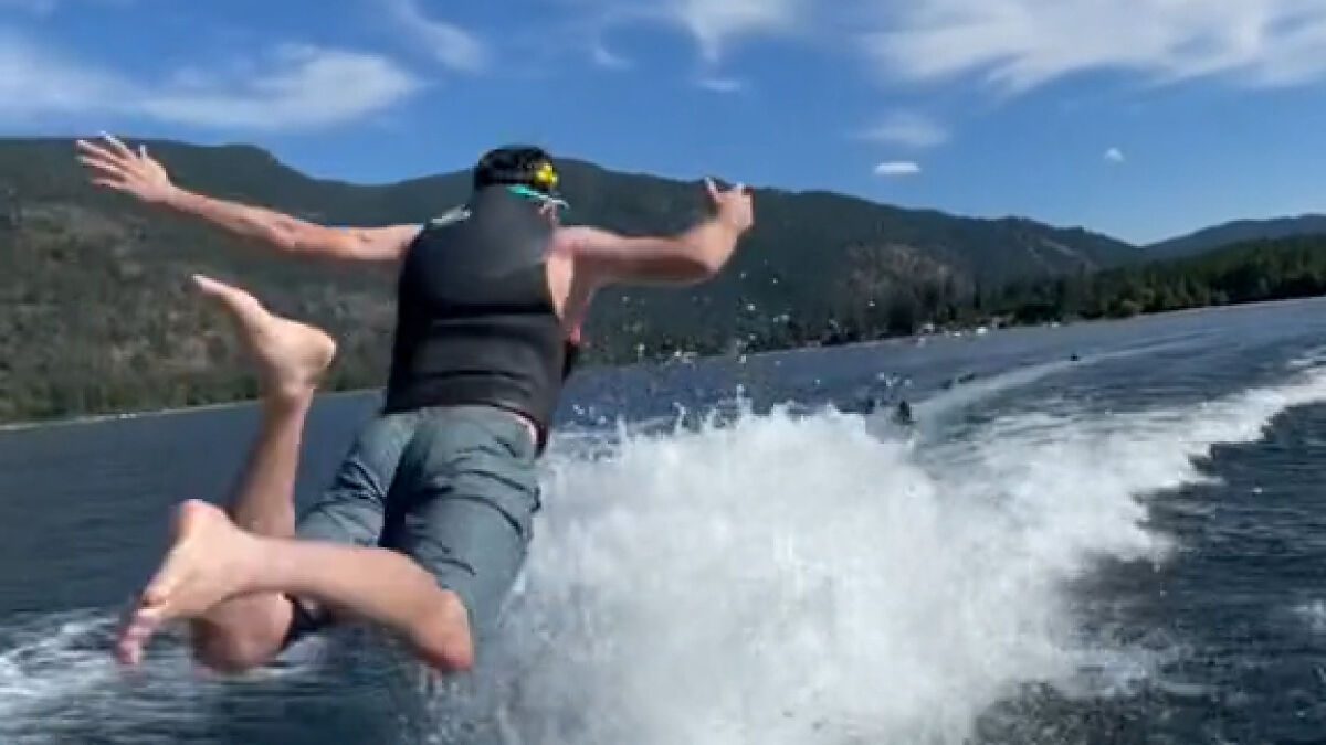 Person diving off a boat into a lake during a dangerous TikTok challenge with water splashing and mountains in the background